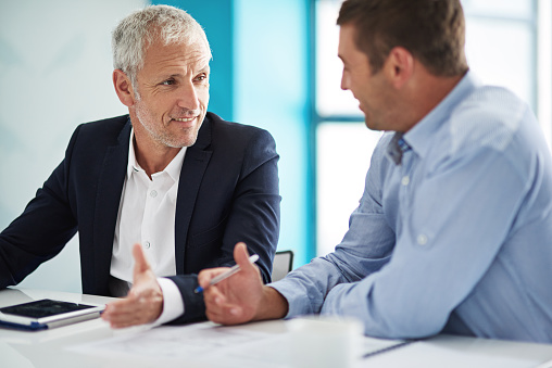 Shot of two businesspeople having a discussion in a corporate office